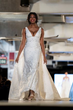 White bridal gowns with flowing trains displayed on a modern fashion runway.