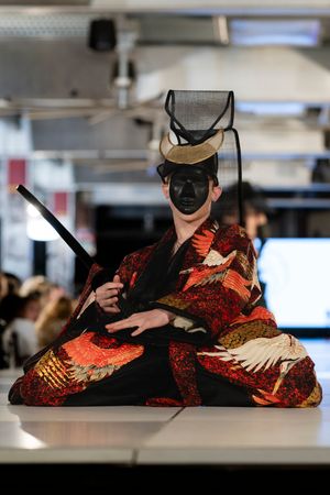 Artistic footwear display featuring red and black patterned boots on fashion runway.