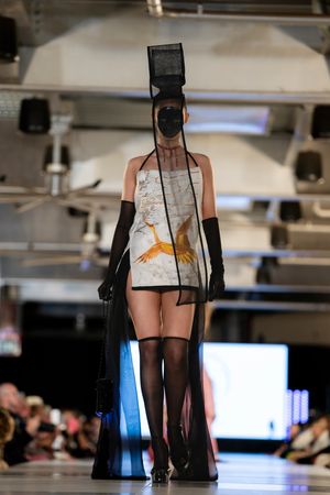 Model showcases avant-garde black and white graphic print design with matching accessories on catwalk.