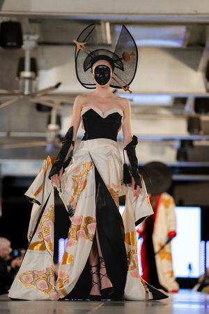 Dramatic black and white dress with artistic prints displayed on fashion runway.