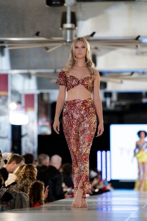 Fashion models walk the runway in sparkling red sequined evening gowns at a glamorous fashion show.