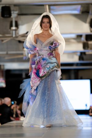Model showcases ethereal blue and pink floral ballgown with dramatic tulle details on runway.
