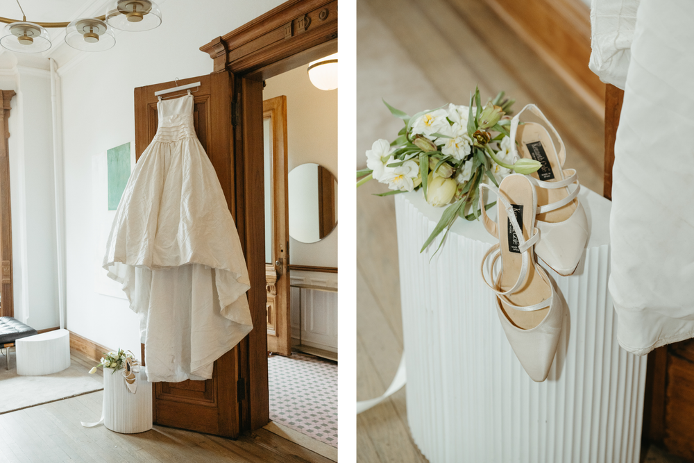 Vintage white dress and floral decorations hanging on wooden wall hooks create an elegant rustic display.