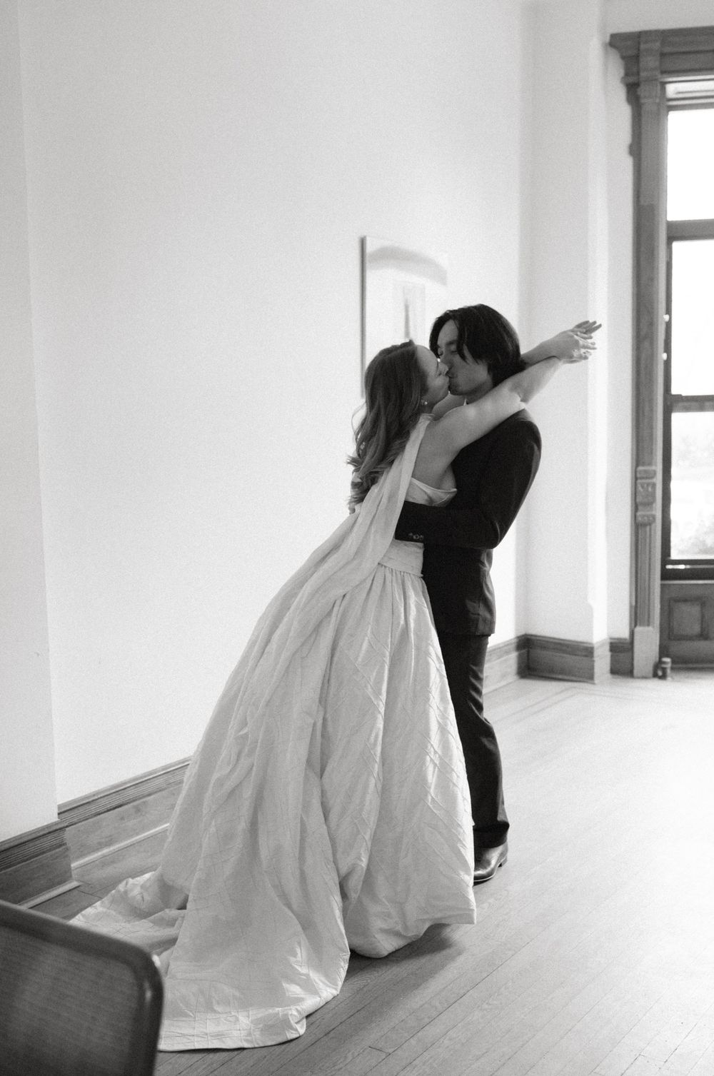 A series of black and white wedding photos showing a couple dancing together in an empty white room.