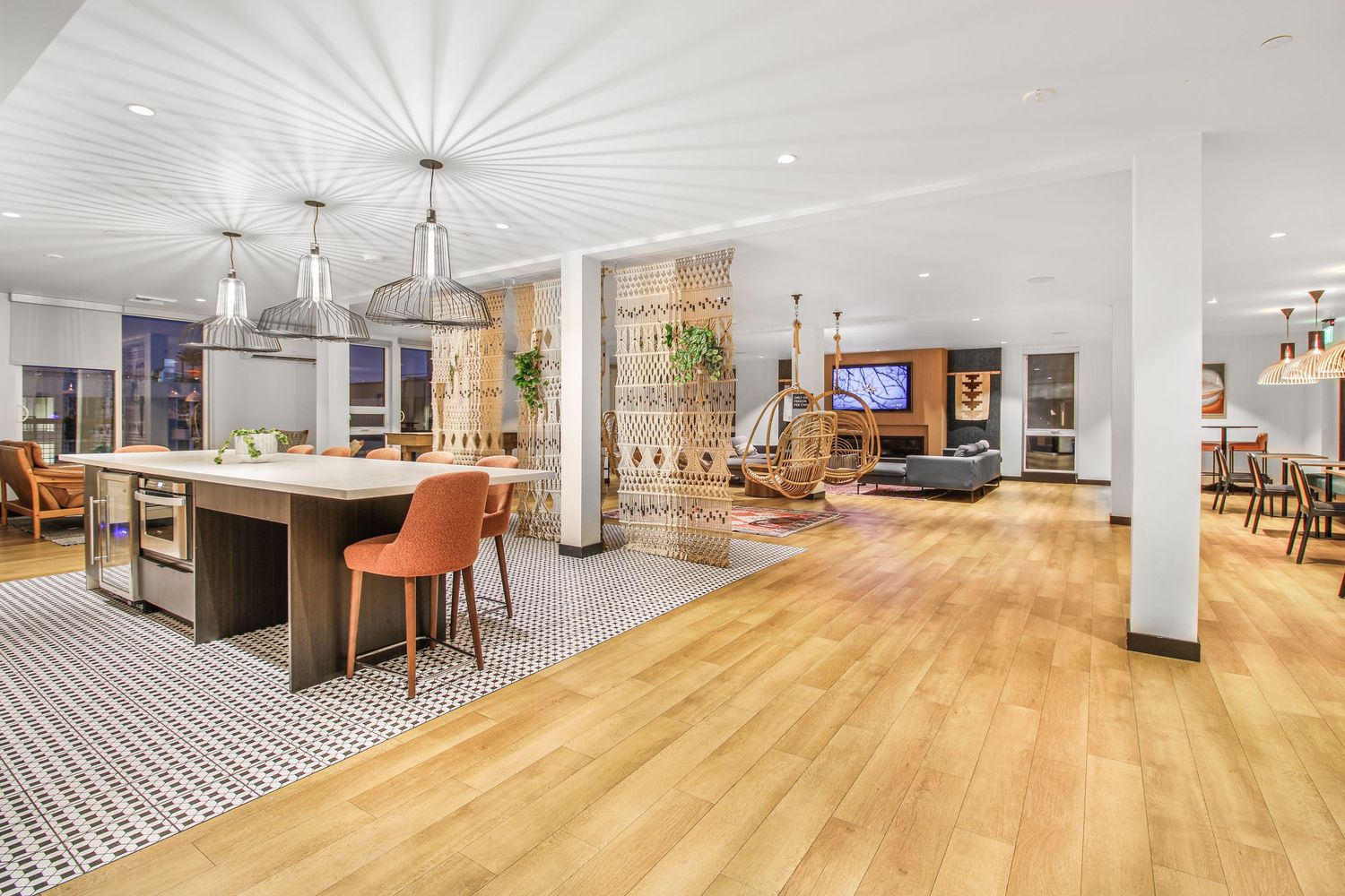 Bright open office interior with hardwood floors, white walls, and contemporary pendant lighting.
