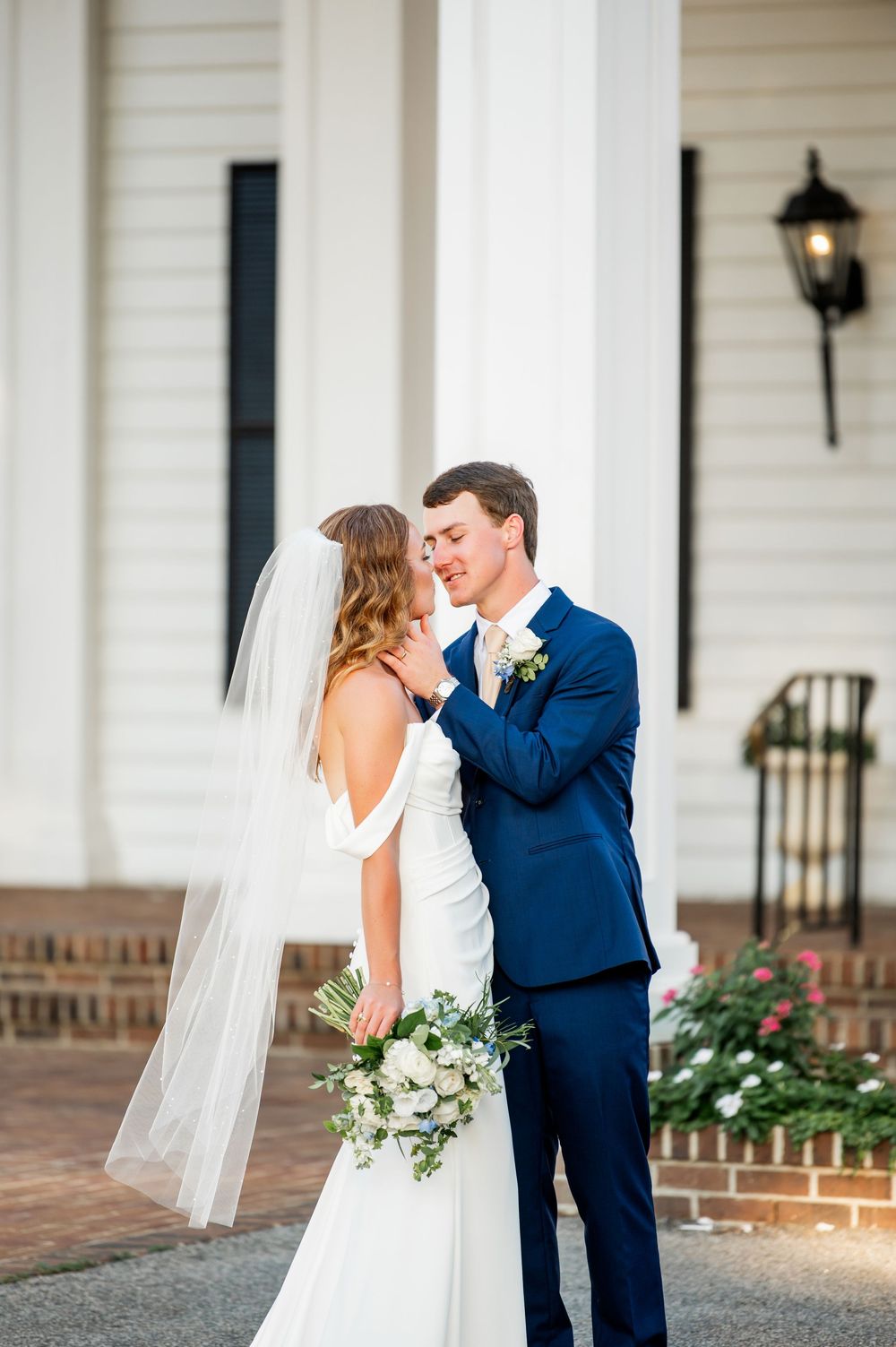 Romantic wedding portraits captured on elegant white porch with brick accents.