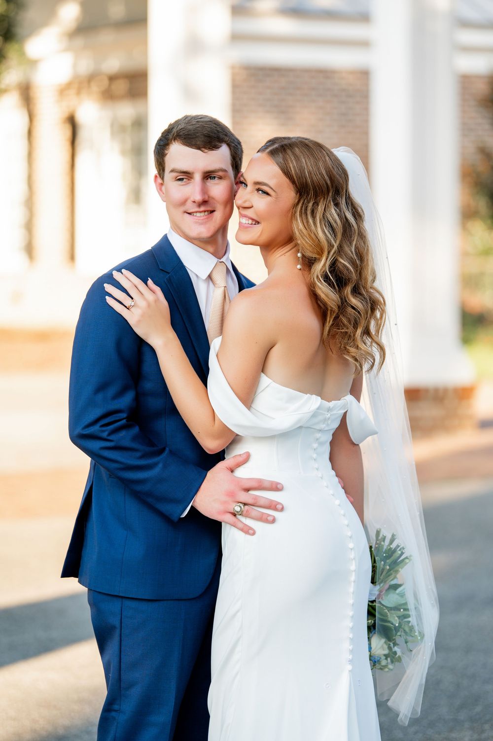 Sun-lit wedding portraits on classic southern porch with white columns.