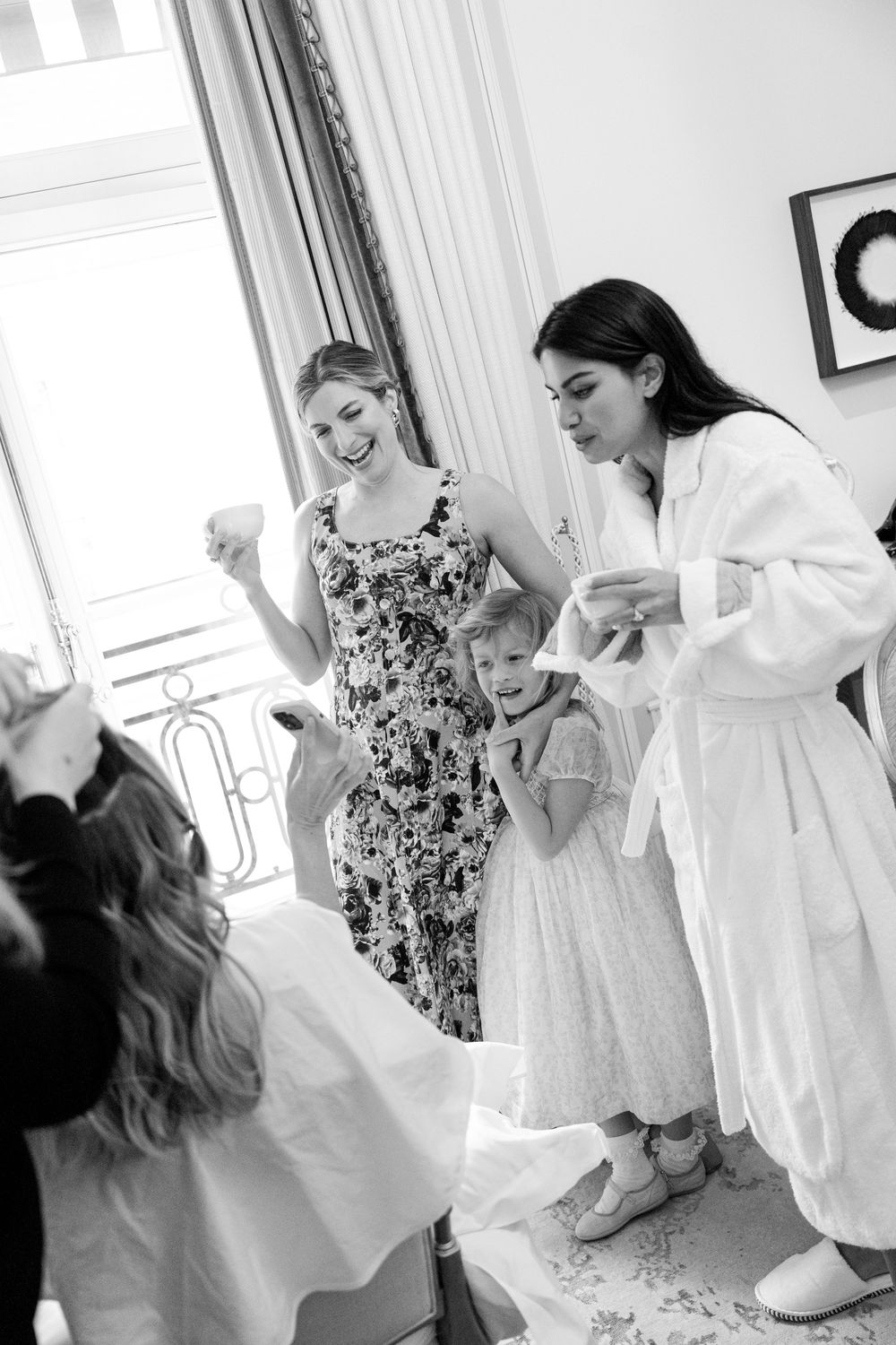 Black and white photo series showing a child in a white dress dancing and twirling in an elegant room.
