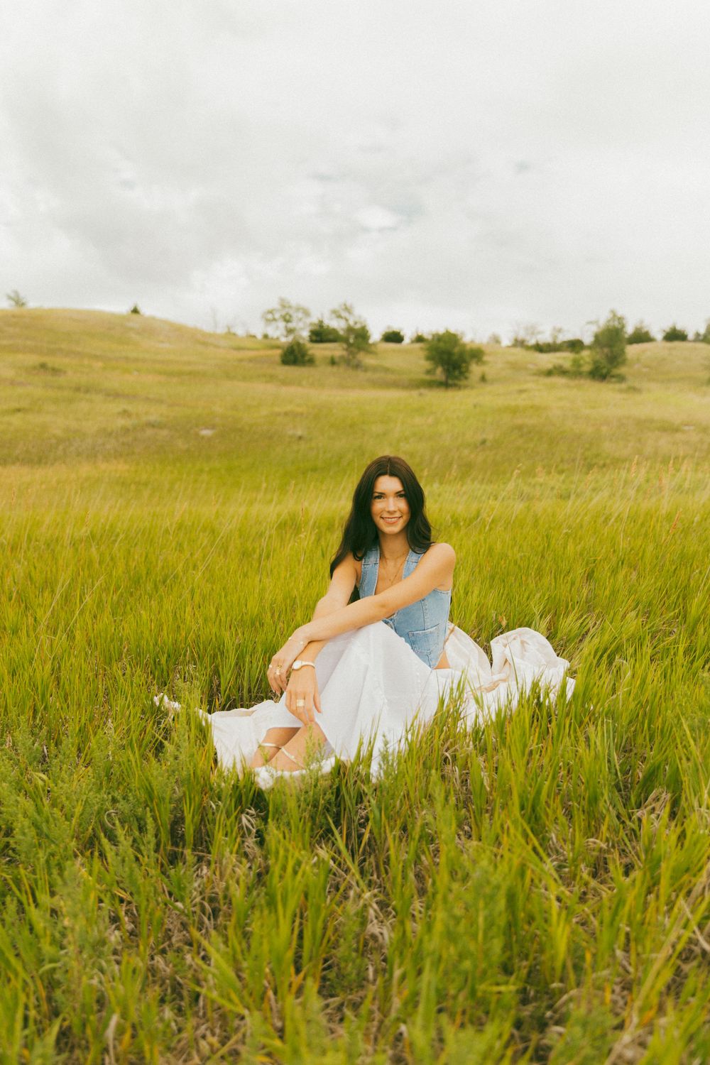 Woman in casual attire posing in a green summer meadow.