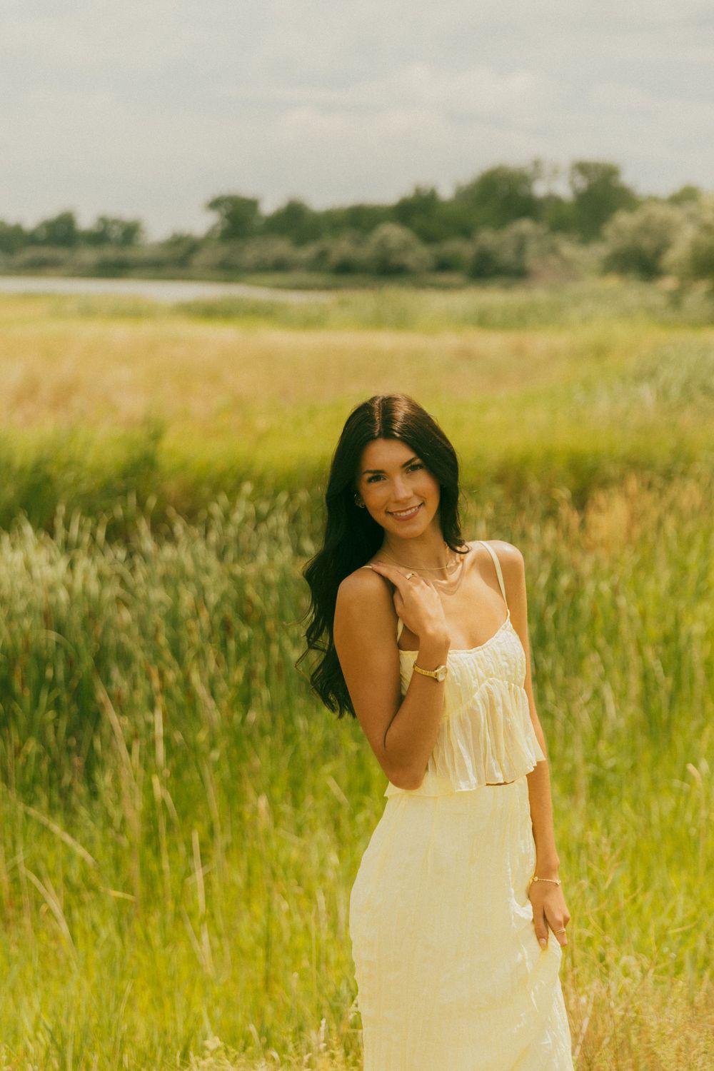 Ethereal portrait session in a sunlit meadow featuring a cream-colored summer dress.