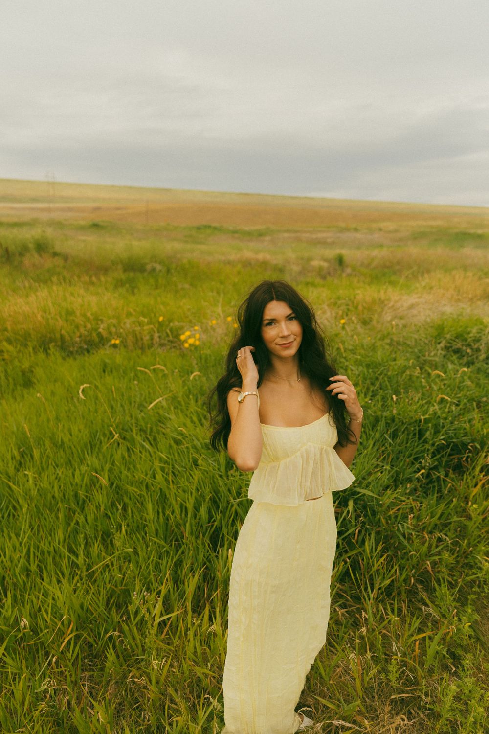 Joyful moments captured in a breezy cream dress against rolling hills and wild grass.