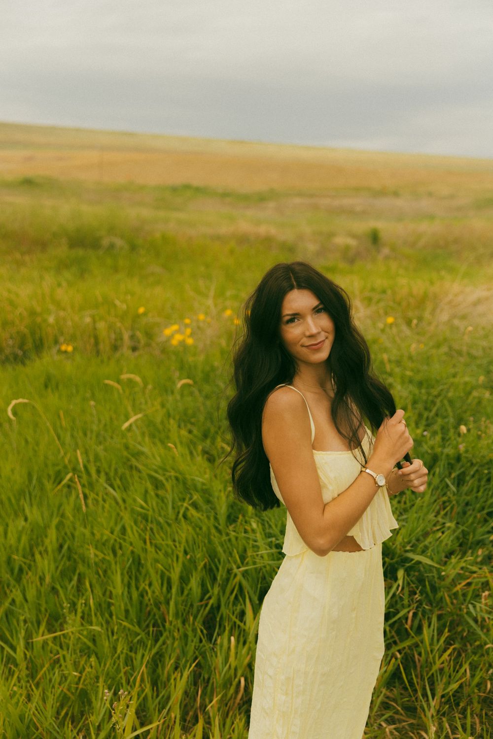 Candid laughter and movement in a summer dress amid a wild grass meadow.