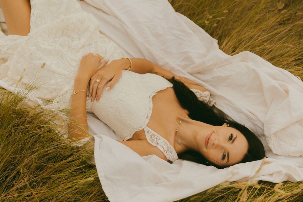 Artistic portrait series in tall grass featuring ethereal white fabric and natural lighting.