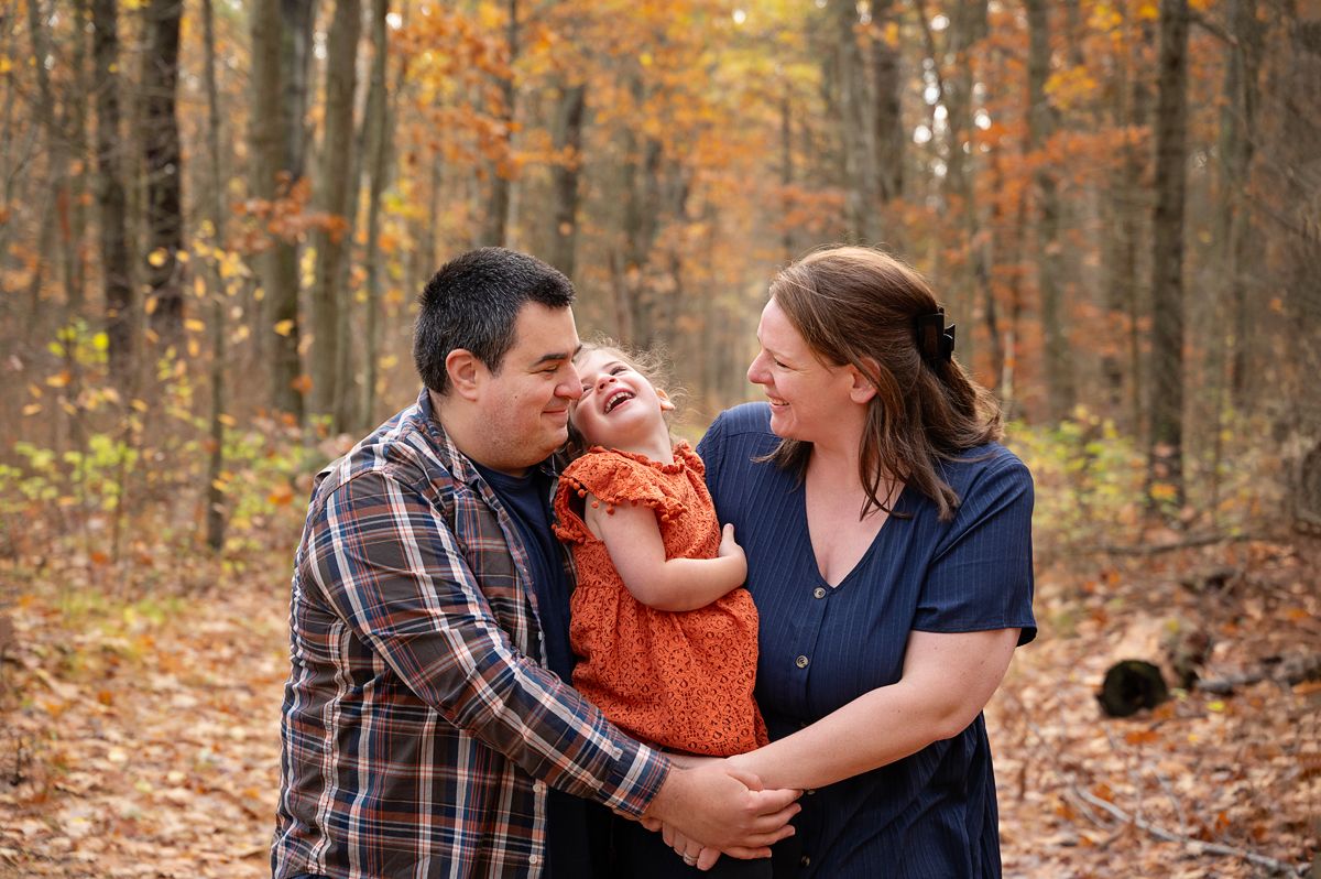 Family of 3, with young daughter in forest in fall in Northumberland