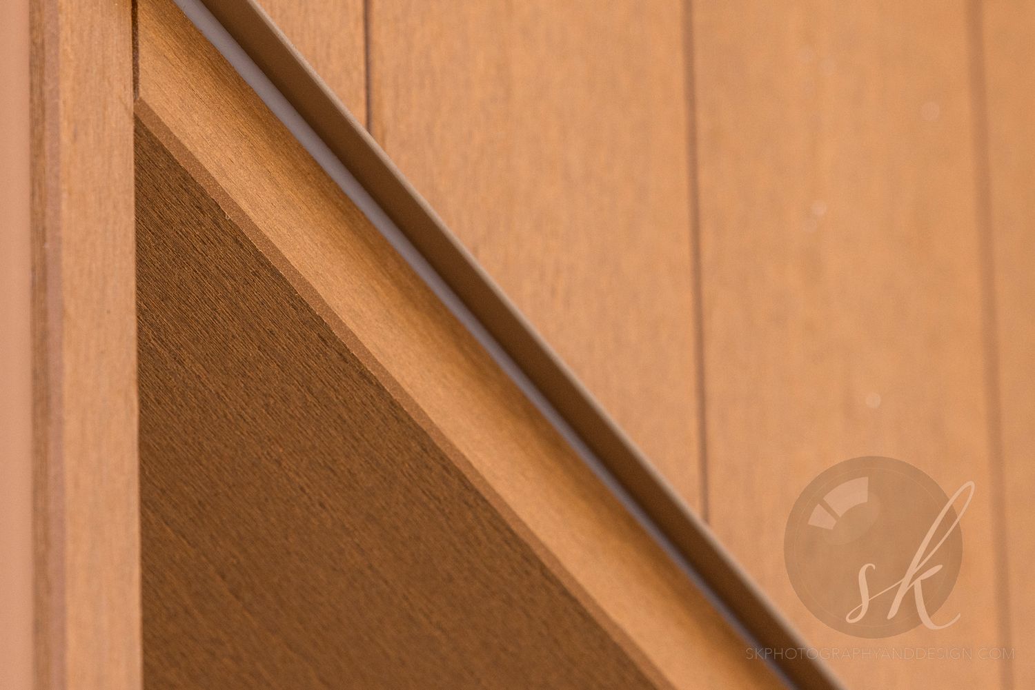 Close-up of a wooden door corner with diagonal trim detail in warm brown tones. A building product made by Geolam.