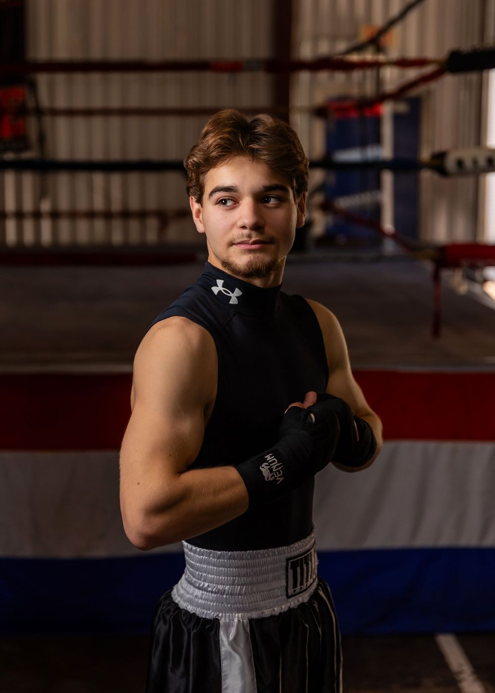 A boxer trains in a gym wearing a black tank top and grey shorts while practicing punches - senior photos in Omaha, NE
