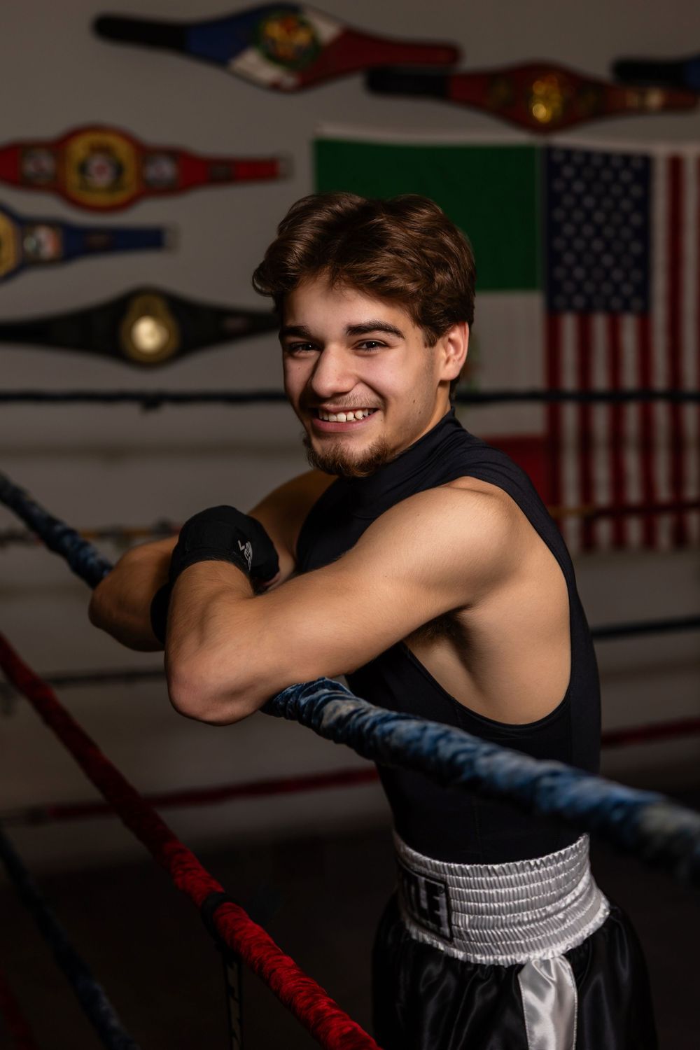 A boxer in black workout gear practices punches in a training gym with American flags on the wall.  - senior photos in Omaha, NE