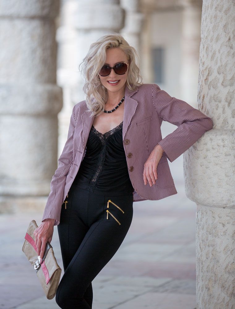 Stylish and fashionable young woman poses against pillar in old city