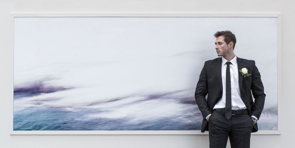 Stylish shot of fashionable young man posing  against large landscape wall art