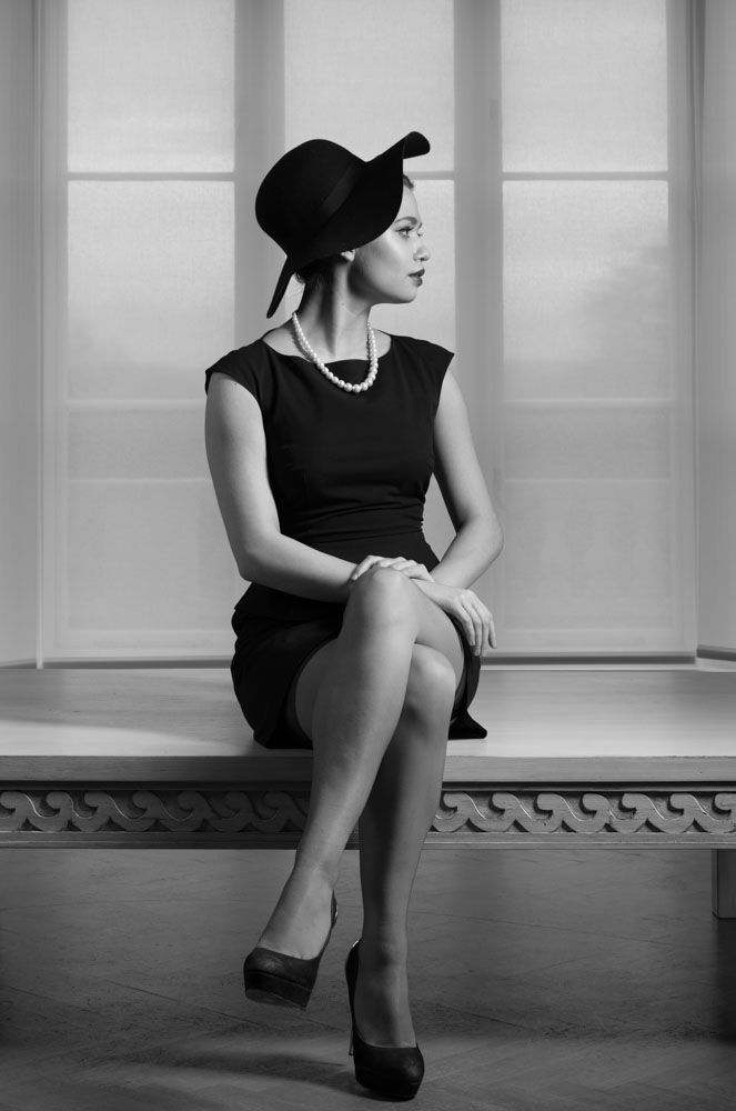 Stylish and fashionable woman sitting in grand lounge of house in black and white