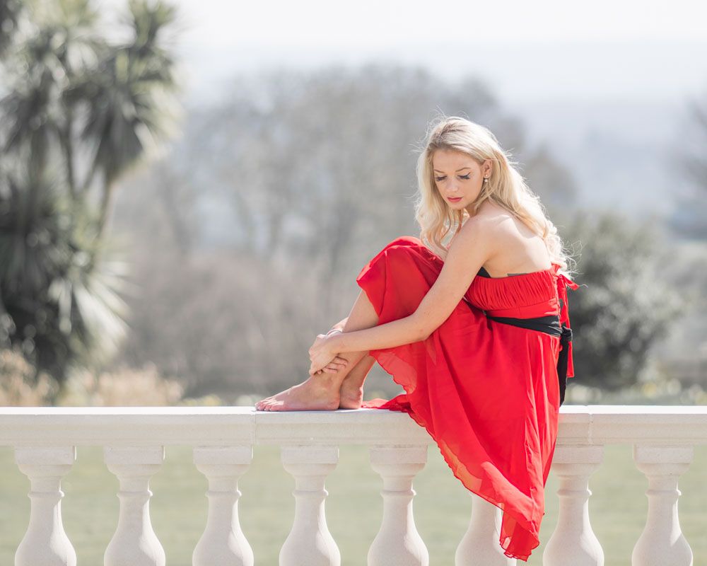 Fashionable woman sitting on balustrade of grand house