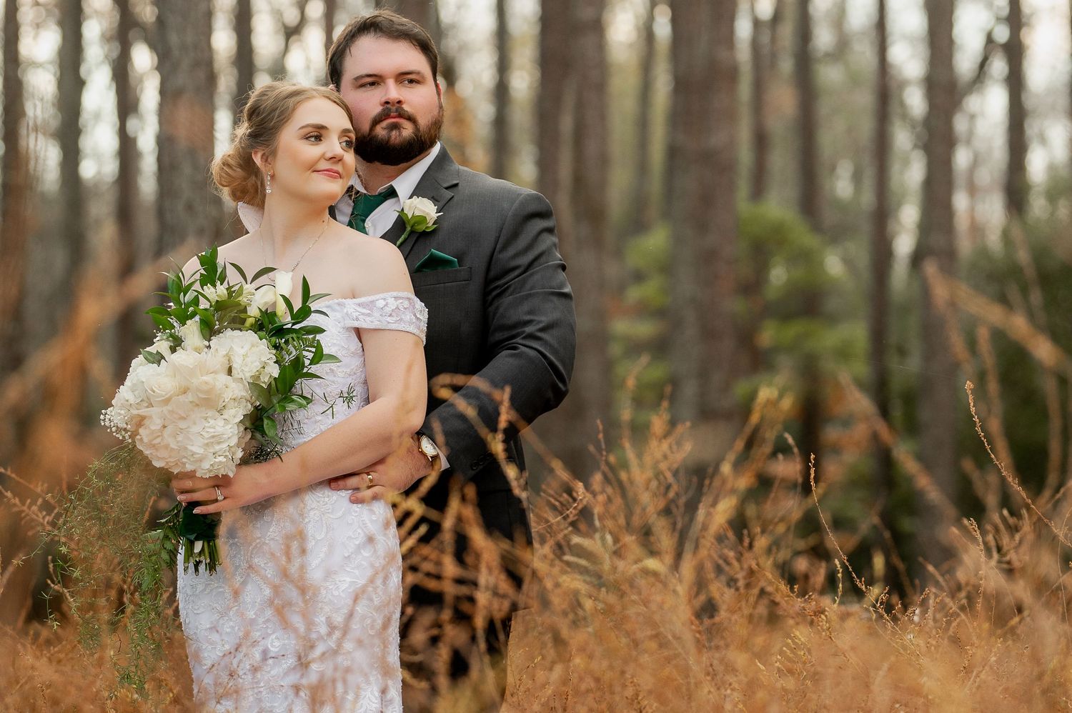 A romantic autumn wedding photoshoot in a wooded area with pine trees and golden foliage.