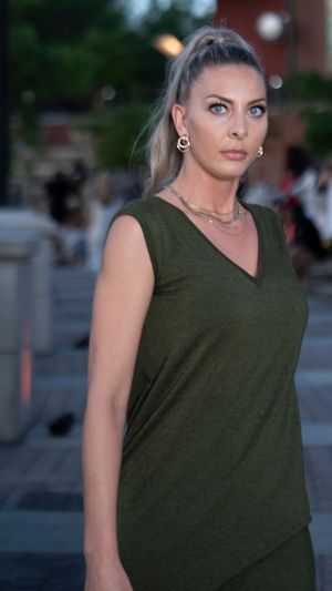 Person in olive green sleeveless top poses outdoors during evening photoshoot.