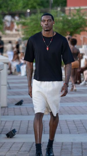 Casual black t-shirt and white shorts ensemble with pendant necklace styled for summer fashion show.