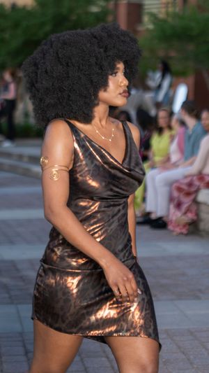 Metallic bronze slip dress with cowl neckline showcased during outdoor fashion event.