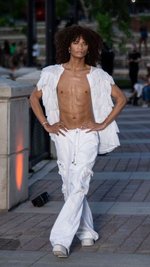 All-white deconstructed outfit showcased during outdoor evening fashion presentation.