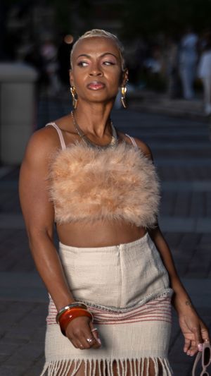 A model showcases a cream-colored dress with feather trim during an evening runway show.