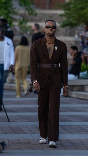 A model walks the runway in a brown monochromatic outfit with sunglasses.