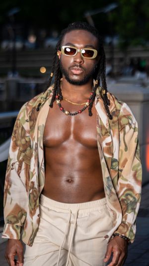Fashion model in camo jacket and cream shorts striking a pose on stone pavement.