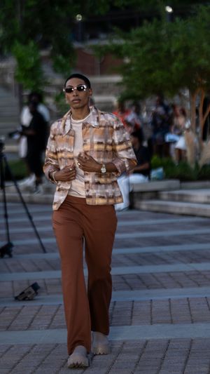 Person wearing patterned top and brown pants walking on brick pavers in an urban plaza.