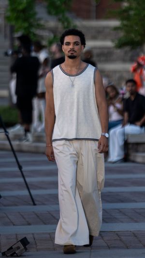 Model walks runway in minimalist white sleeveless jumpsuit ensemble.