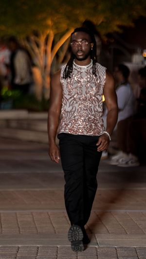 Fashion show featuring a sparkly beige top paired with black pants on a stone walkway.
