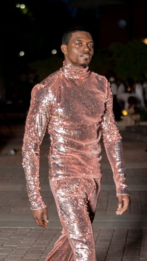 Performer dancing in shimmering rose gold sequined bodysuit on outdoor stage.