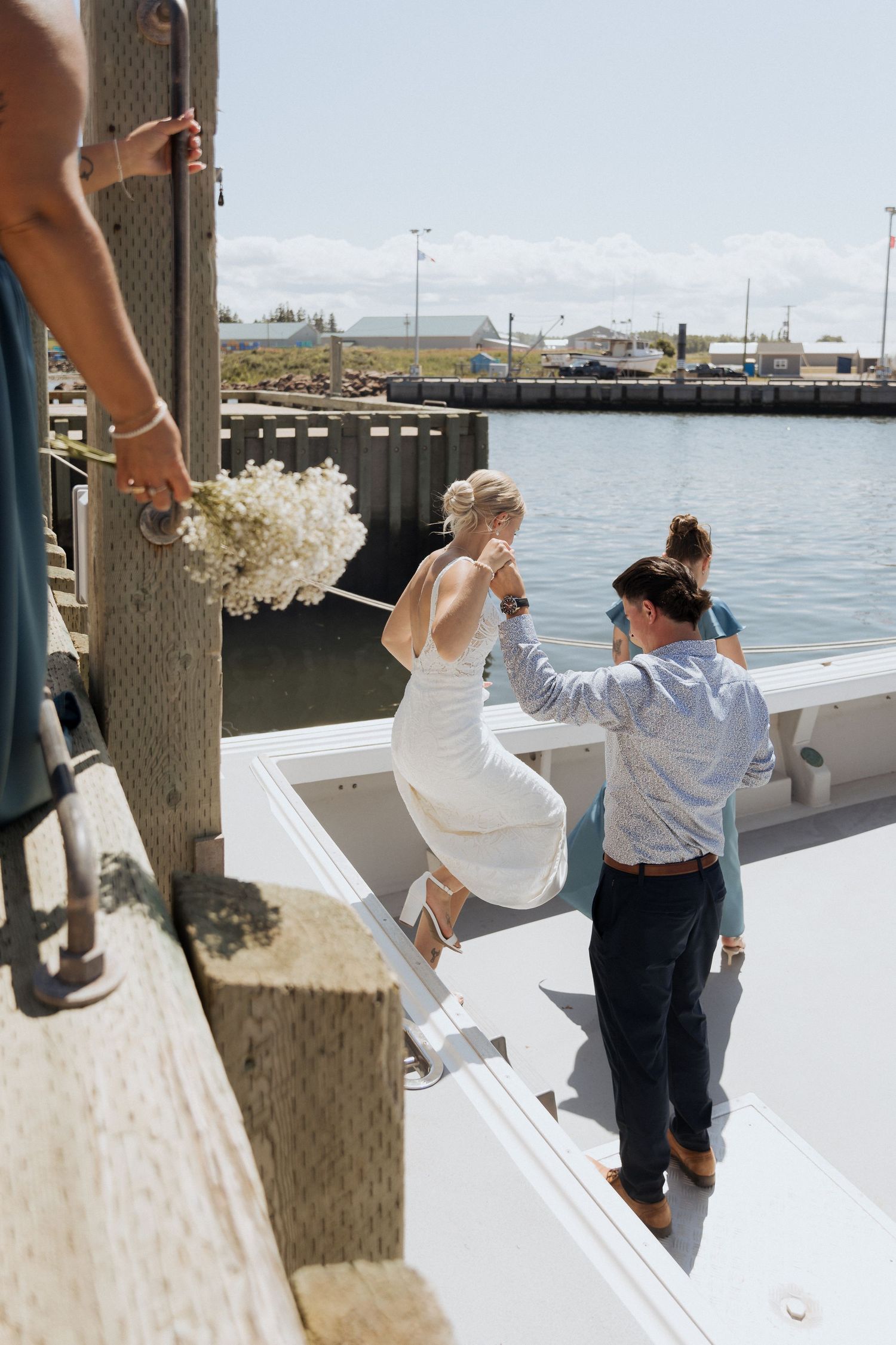 family helping bride down onto boat for wedding portraits in Shediac Bay, wedding photography in Moncton New Brunswick, timeless wedding