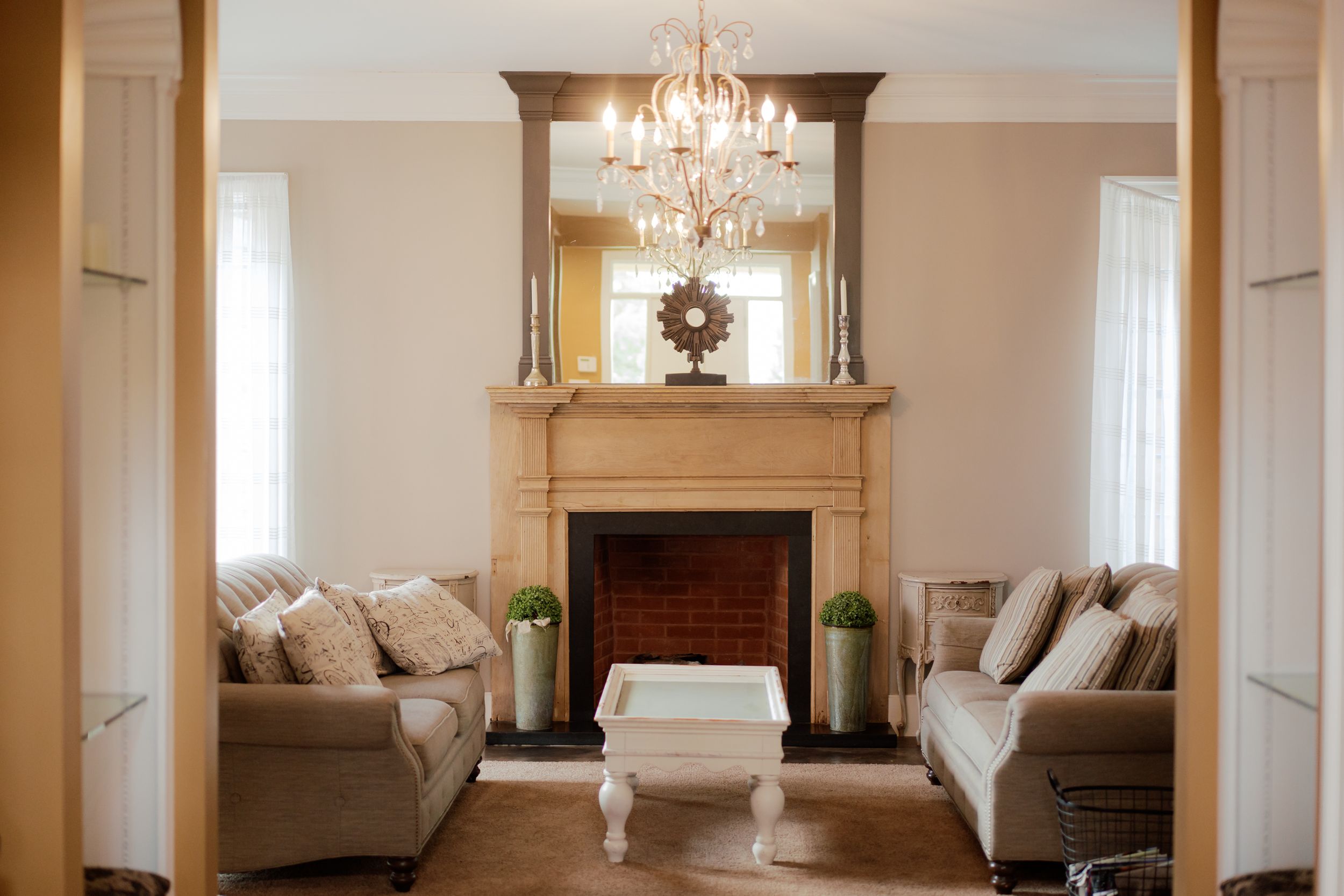 Elegant white room with chandelier and ornate crown molding in natural light.