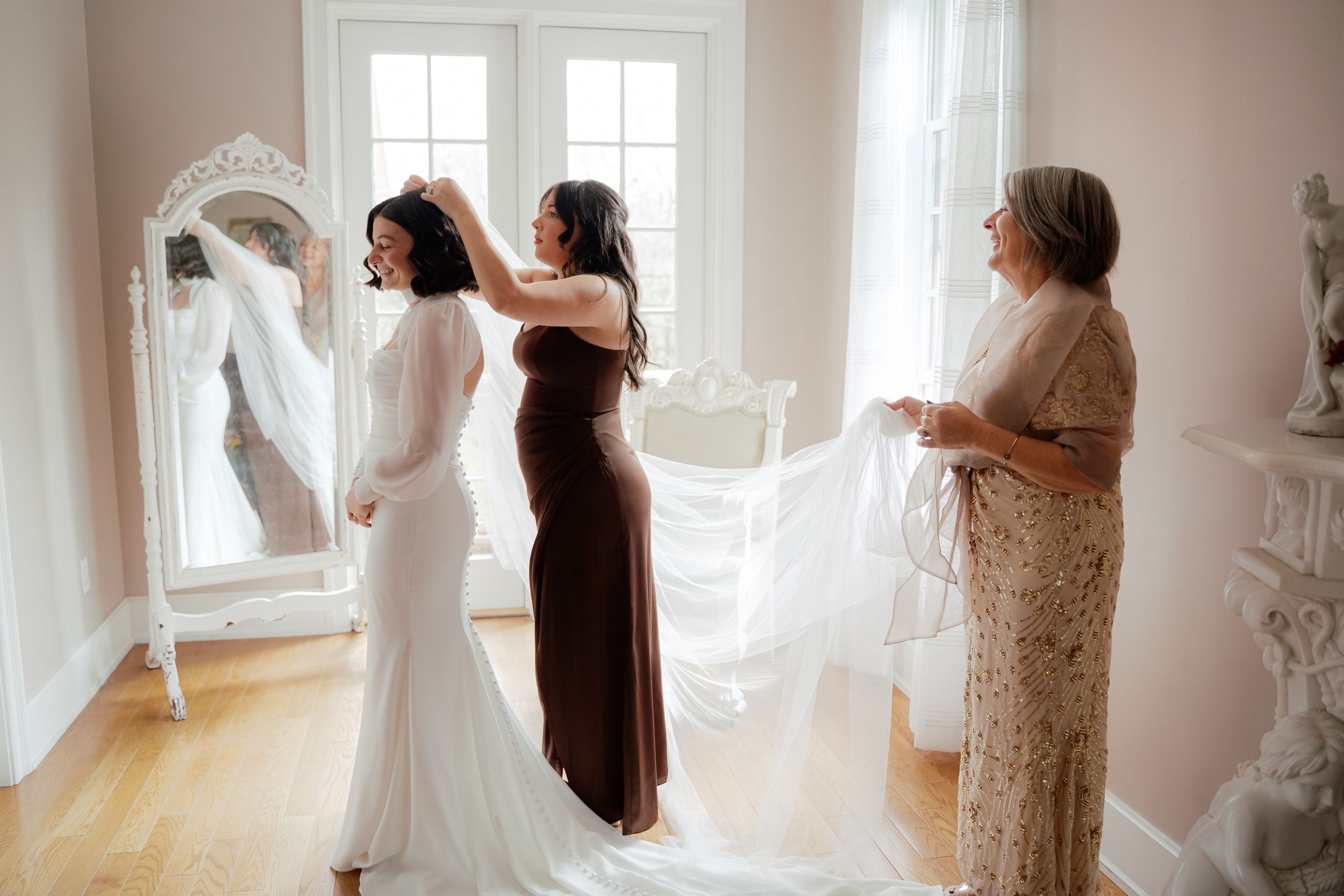 Sunlit room with flowing white curtains and wedding preparations in progress.