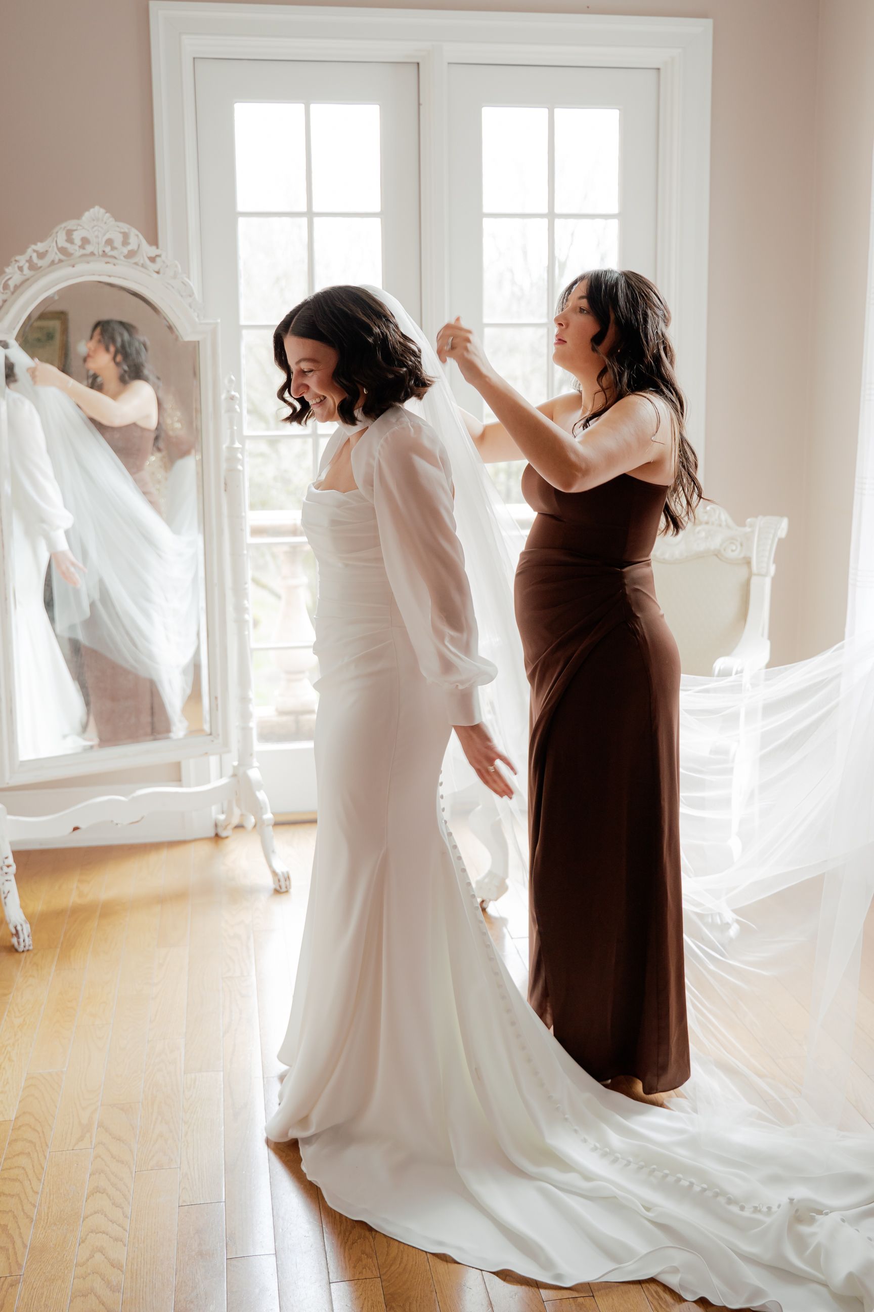 Wedding preparation scene with flowing white dress and brown accents in a bright sunlit room.