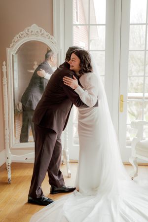 Wedding couple sharing intimate moment in sunlit room with ornate decor.