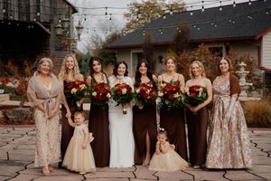 Wedding party in burgundy and gold dresses posing together outdoors.