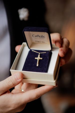 Small gold cross necklace being presented in a jewelry box.