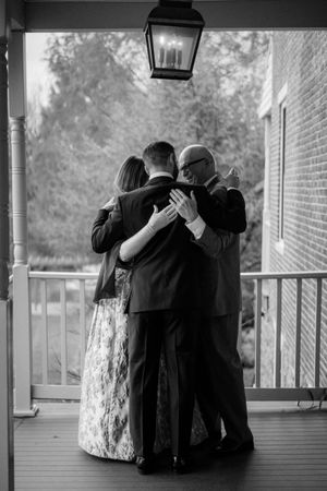 Black and white photo of formal gathering on a covered porch with white railings.