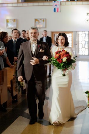 Wedding processional in a church with people walking down the aisle in formal attire.
