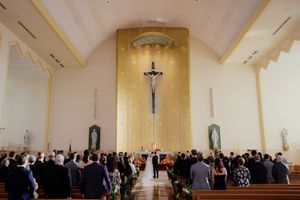 A church sanctuary interior with wooden beams and chandeliers decorated for a wedding ceremony.
