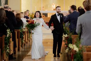Wedding ceremony guests gathered in a church with floral decorations along the aisle.