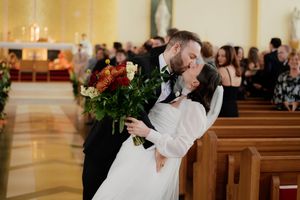 Wedding ceremony taking place in a church with yellow walls and decorative greenery.
