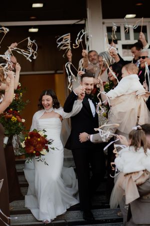 Wedding celebration with guests throwing streamers and confetti as the couple exits.
